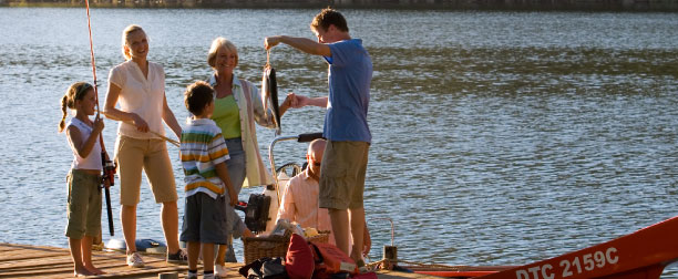 family holding up a fish standing on the dock after a fishing trip 